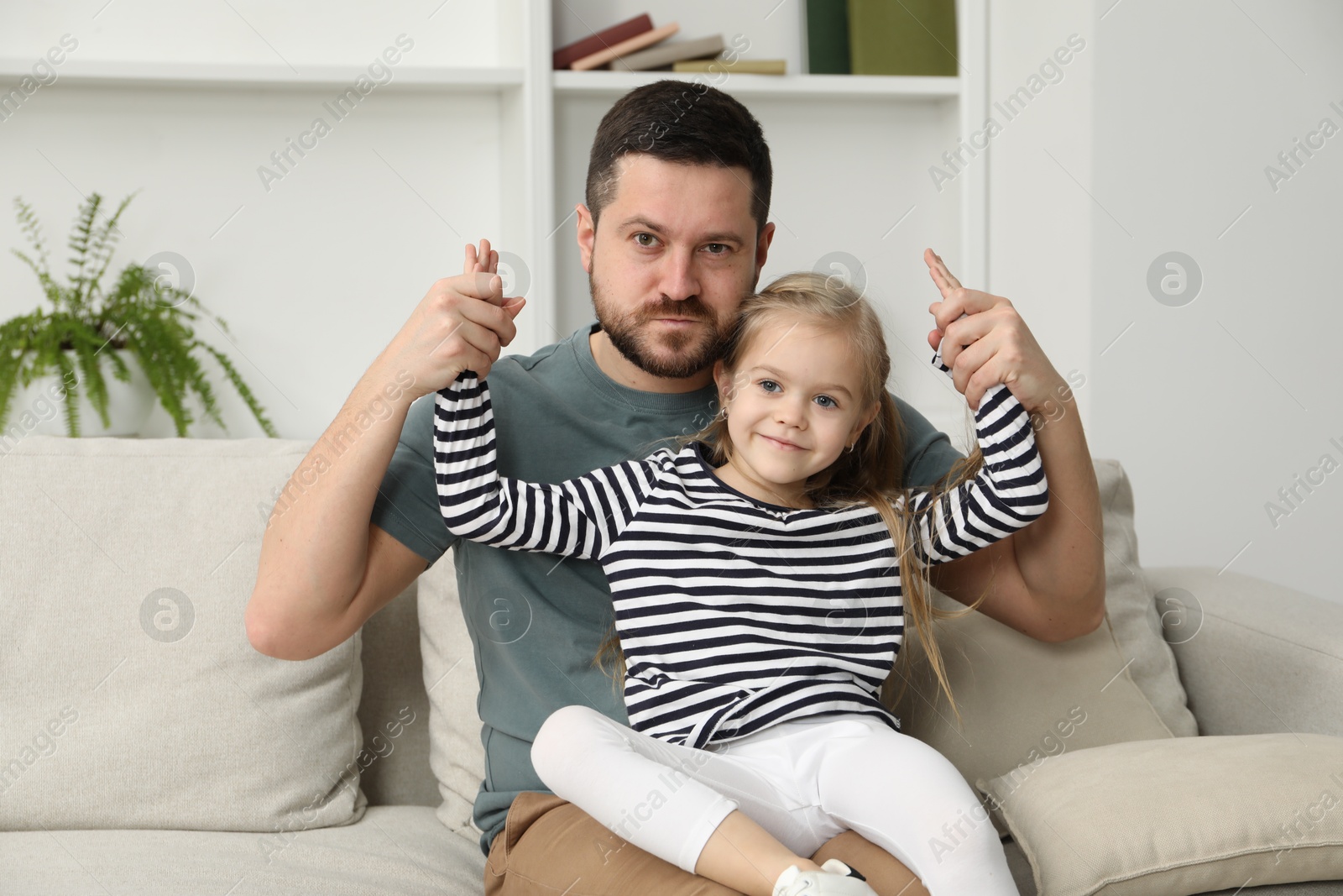 Photo of Father and his cute little daughter on sofa at home