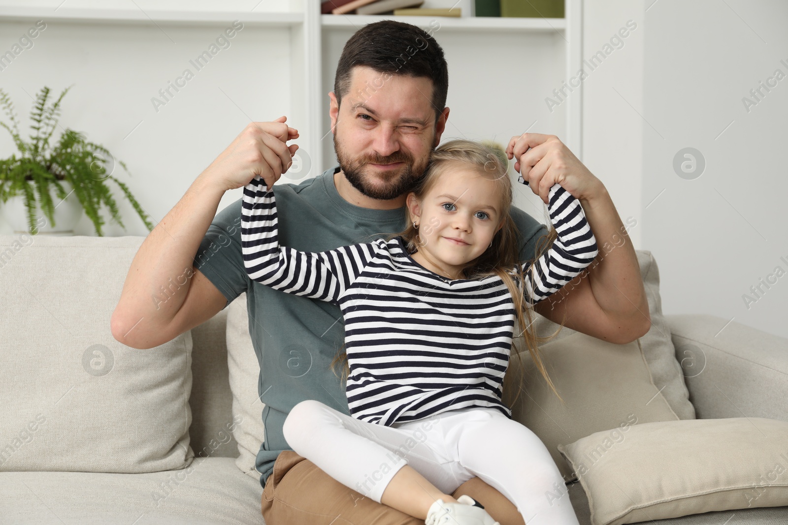 Photo of Father and his cute little daughter on sofa at home