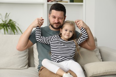 Photo of Father and his cute little daughter on sofa at home