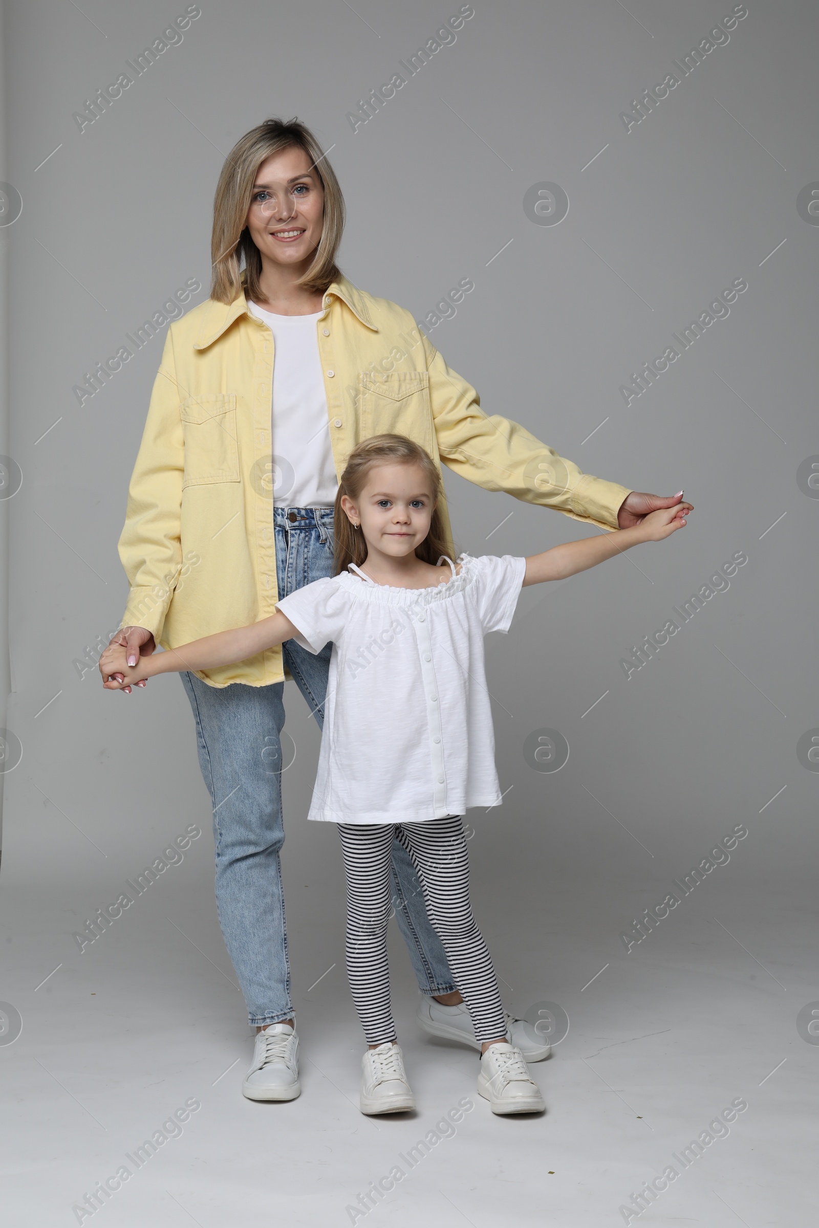 Photo of Happy mother and her cute little daughter on light background