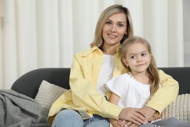 Happy mother and her cute little daughter on sofa at home