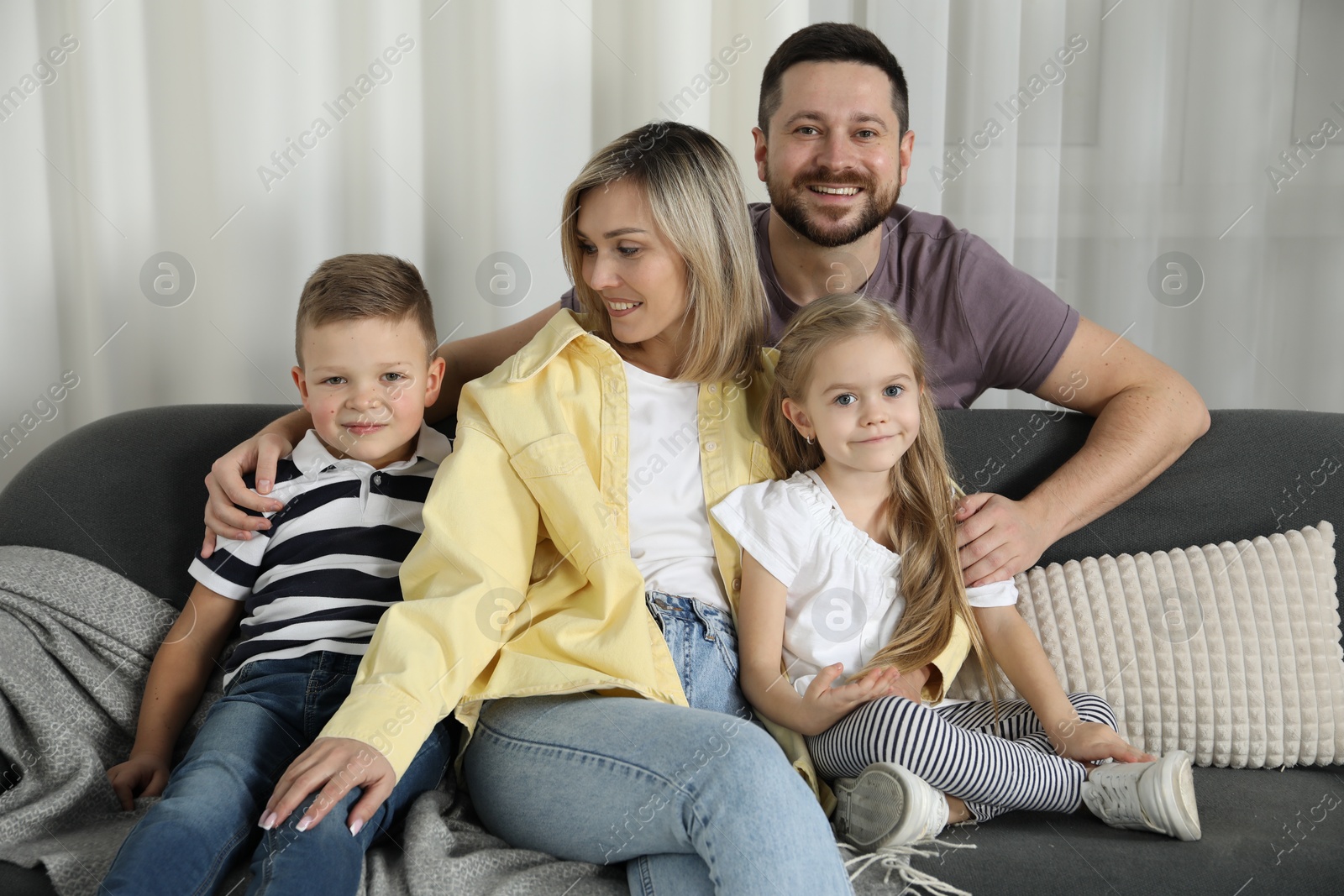 Photo of Happy parents and their children on sofa at home