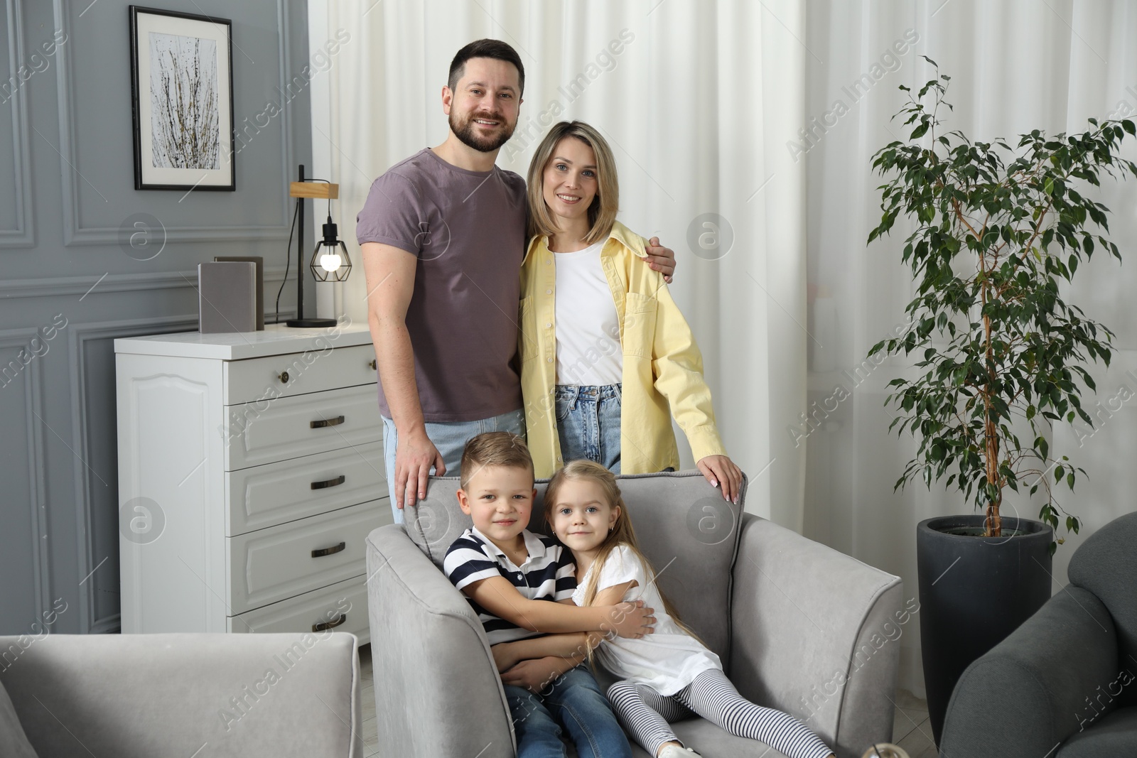 Photo of Happy parents and their children in armchair at home