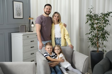 Happy parents and their children in armchair at home