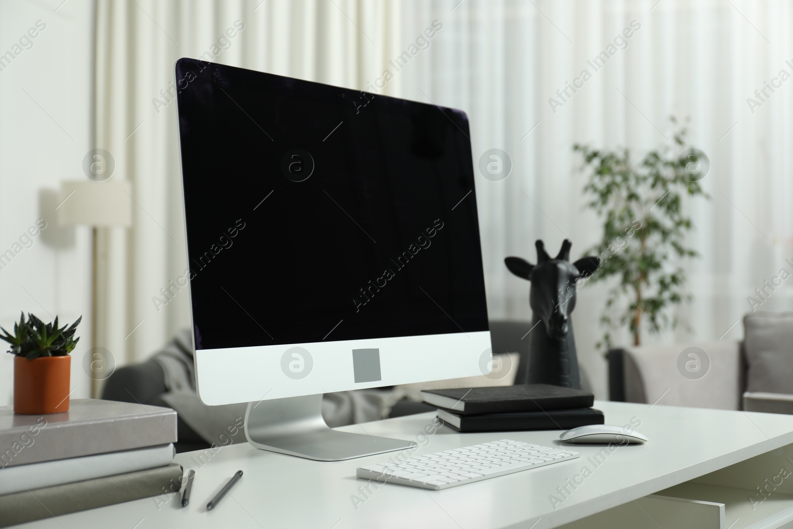 Photo of Modern workplace with computer and stationery on white desk indoors