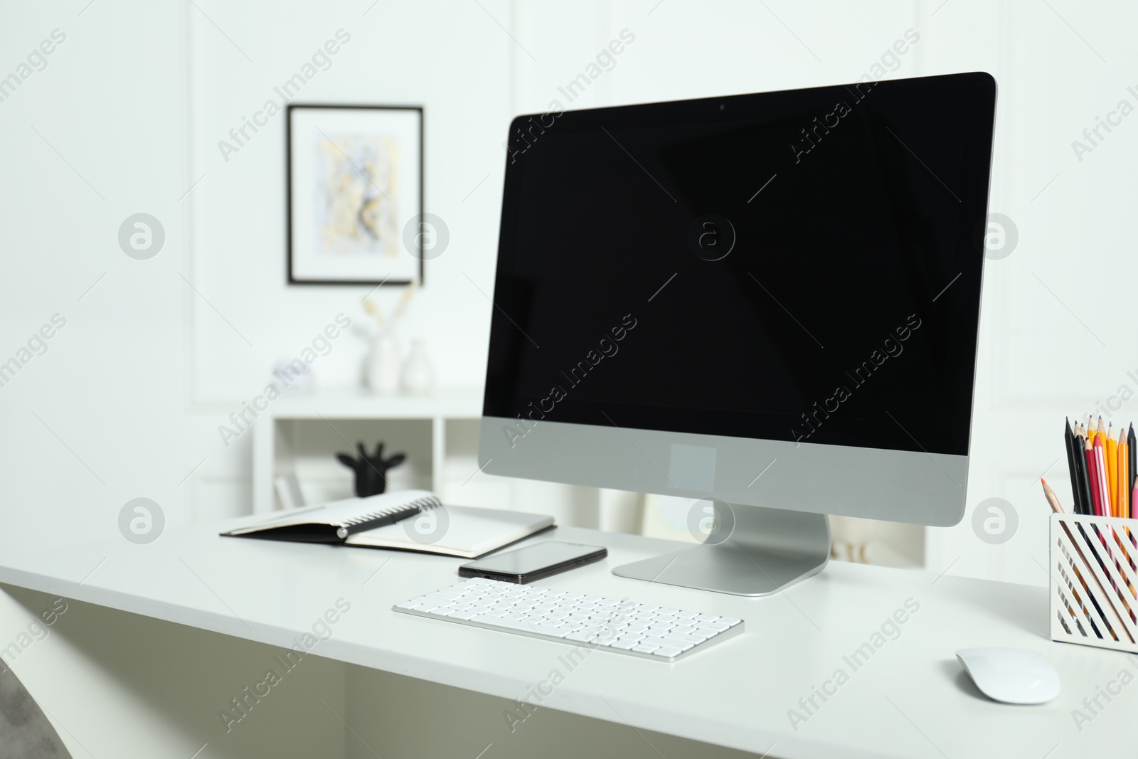 Photo of Modern workplace with computer and stationery on white desk indoors