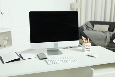 Photo of Modern workplace with computer and stationery on white desk indoors