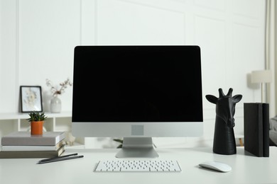 Photo of Modern workplace with computer and stationery on white desk indoors