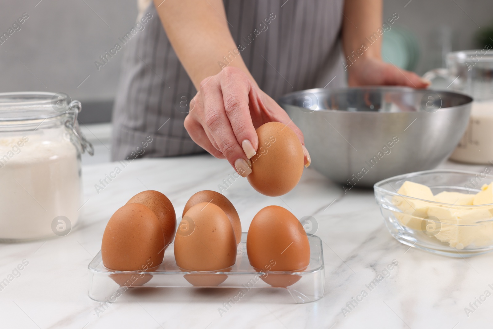 Photo of Making dough. Woman with fresh eggs at white marble table, closeup