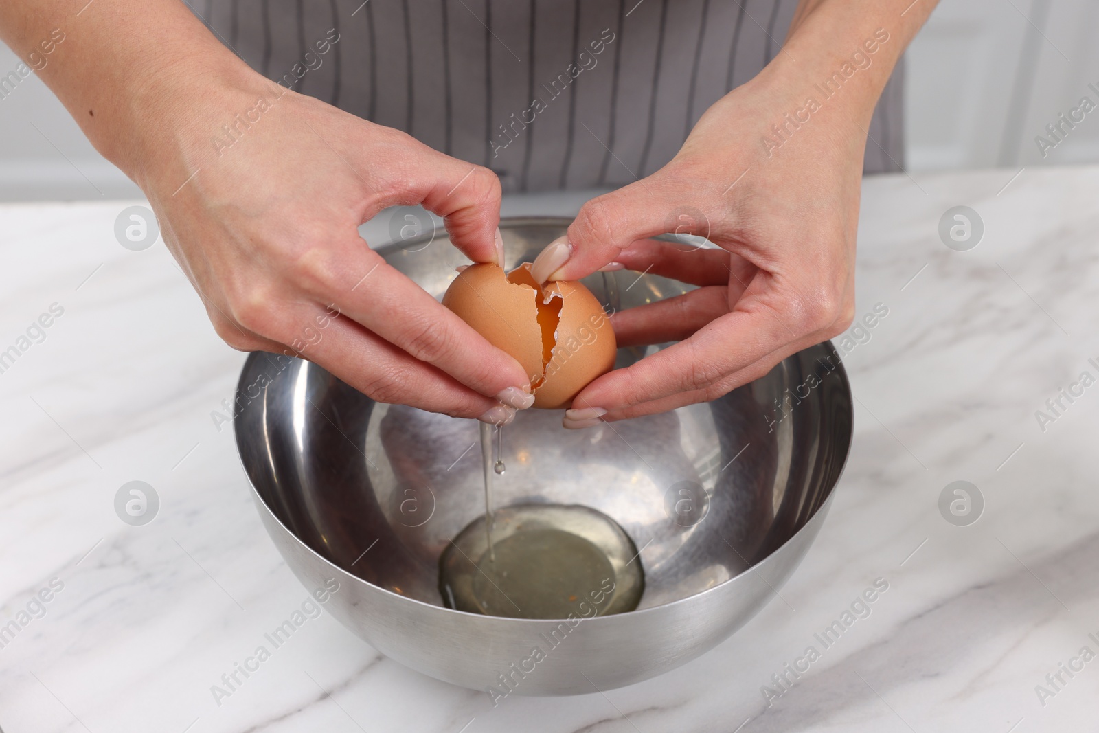 Photo of Making dough. Woman adding egg into bowl at white marble table, closeup