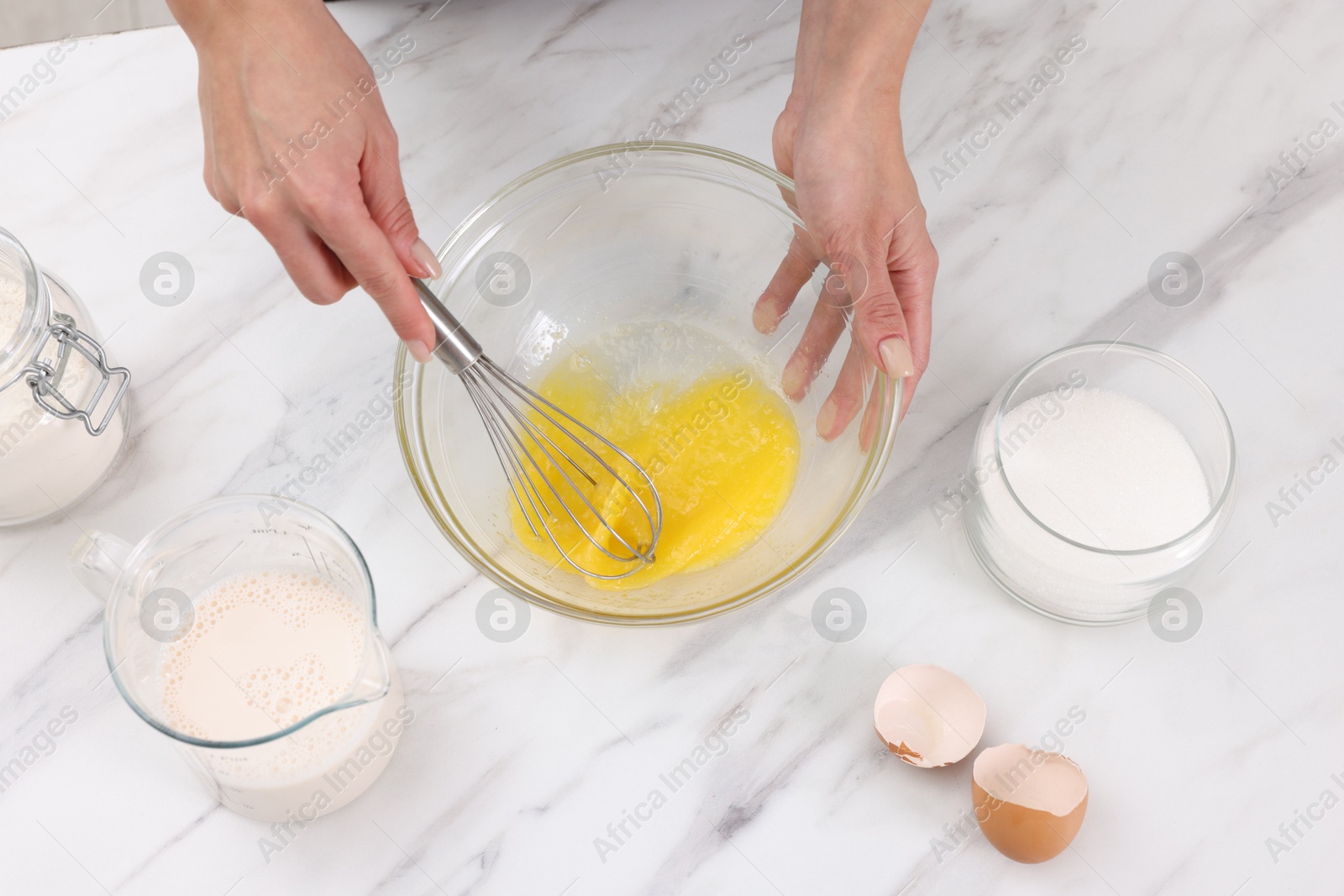 Photo of Woman making dough at white marble table indoors, above view