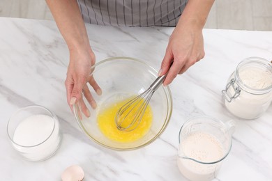 Photo of Woman making dough at white marble table indoors, above view