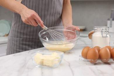 Photo of Woman making dough at white marble table indoors, closeup