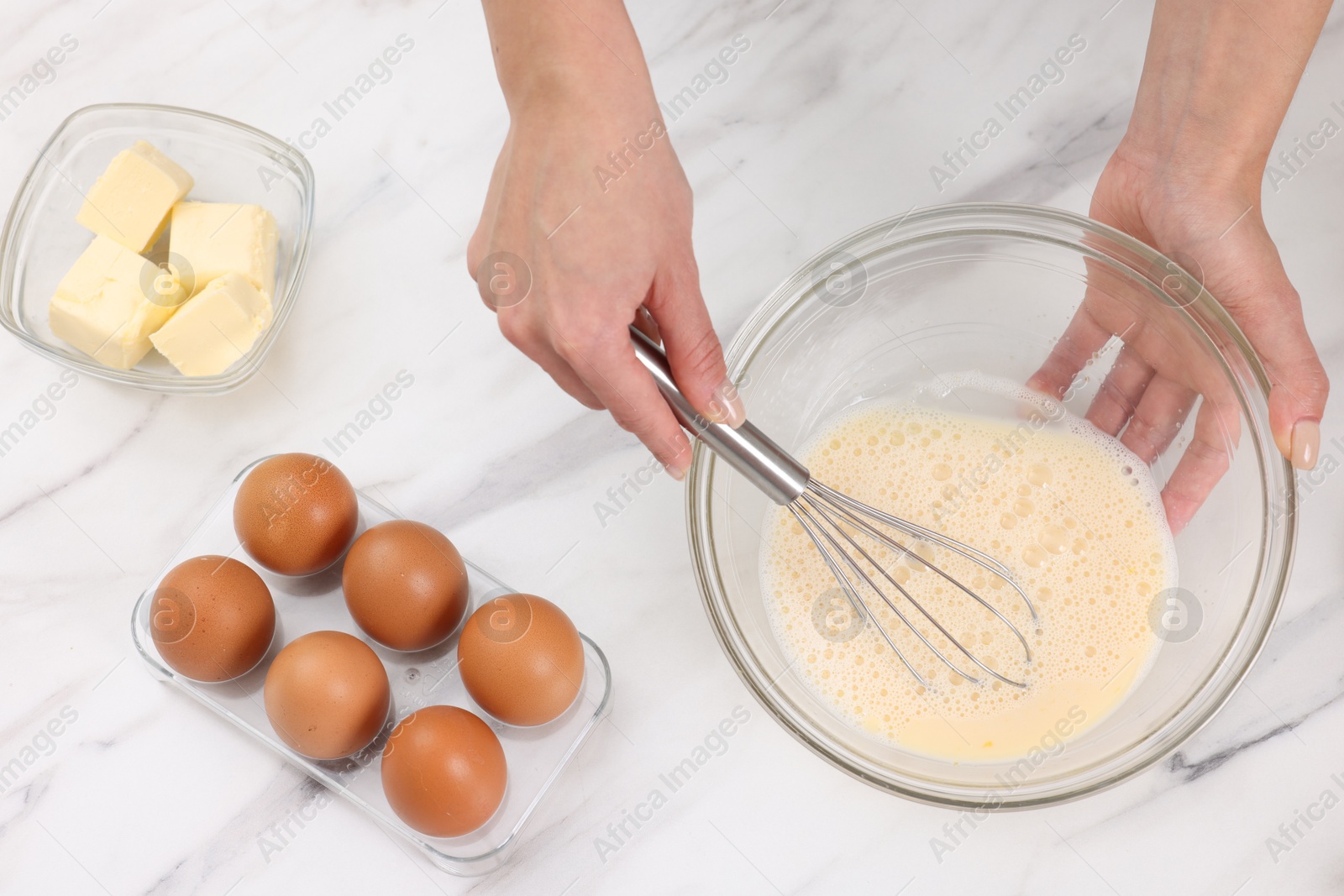 Photo of Woman making dough at white marble table indoors, above view