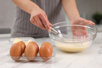 Photo of Woman making dough at white marble table indoors, selective focus