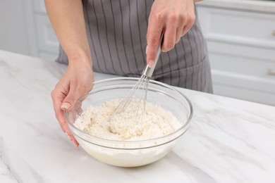 Photo of Woman making dough at white marble table indoors, closeup