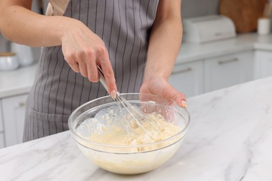 Photo of Woman making dough at white marble table indoors, closeup