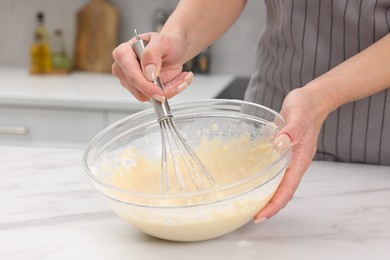 Photo of Woman making dough at white marble table indoors, closeup