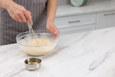 Photo of Woman making dough at white marble table indoors, closeup. Space for text