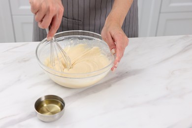 Photo of Woman making dough at white marble table indoors, closeup