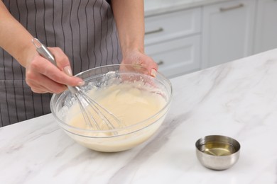 Photo of Woman making dough at white marble table indoors, closeup. Space for text