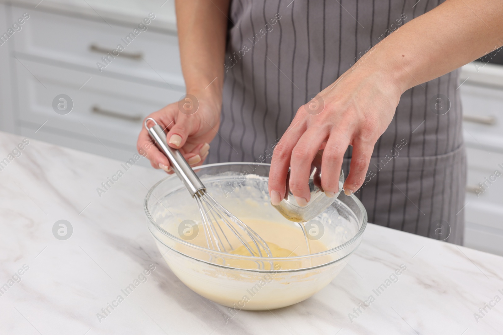 Photo of Woman adding oil into bowl with dough at white marble table, closeup