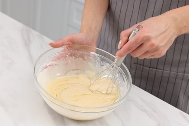 Photo of Woman making dough at white marble table indoors, closeup