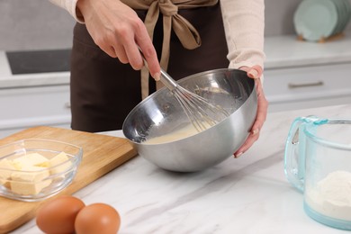 Photo of Woman making dough at white marble table indoors, closeup