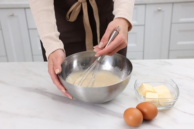 Photo of Woman making dough at white marble table indoors, closeup