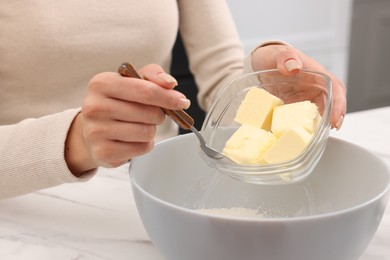 Making dough. Woman adding butter into bowl at white marble table, closeup