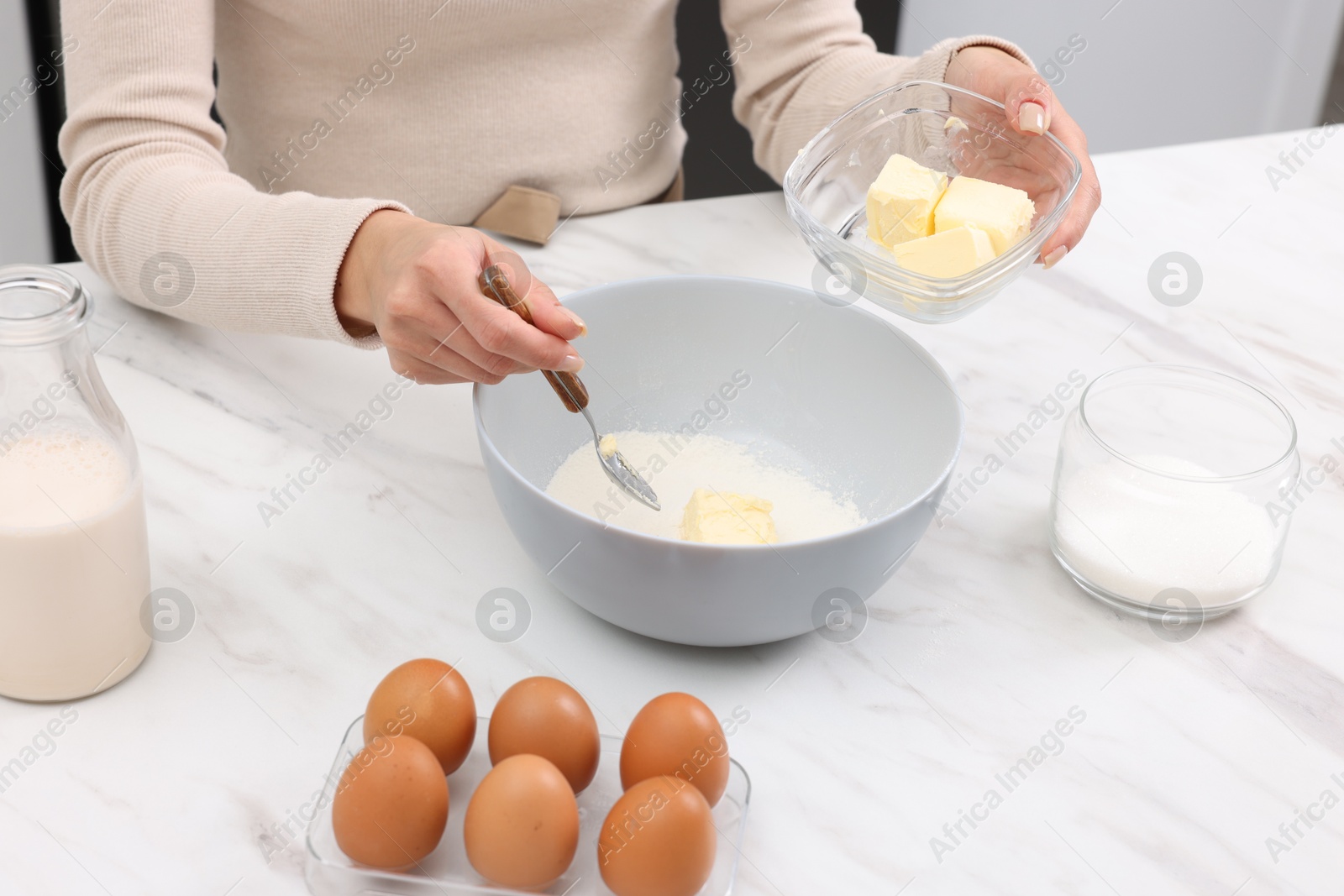 Photo of Making dough. Woman adding butter into bowl at white marble table, closeup