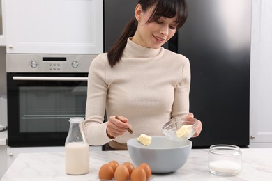 Making dough. Woman adding butter into bowl at white marble table