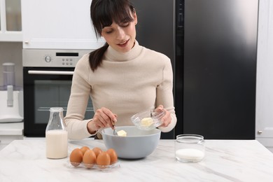 Making dough. Woman adding butter into bowl at white marble table