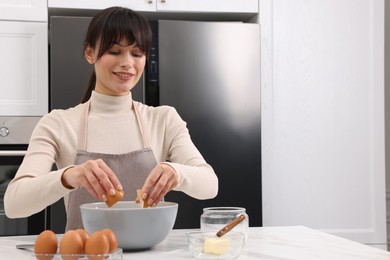 Making dough. Woman adding egg into bowl at white marble table. Space for text