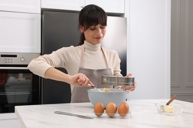 Woman sifting flour into bowl with dough at white marble table