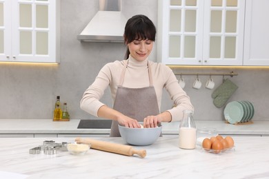 Woman kneading dough in bowl at white marble table