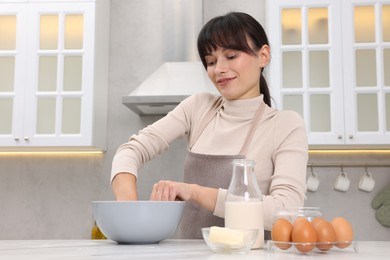 Woman kneading dough in bowl at white marble table