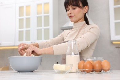 Photo of Woman kneading dough in bowl at white marble table, selective focus