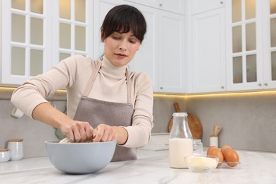 Photo of Woman kneading dough in bowl at white marble table. Space for text