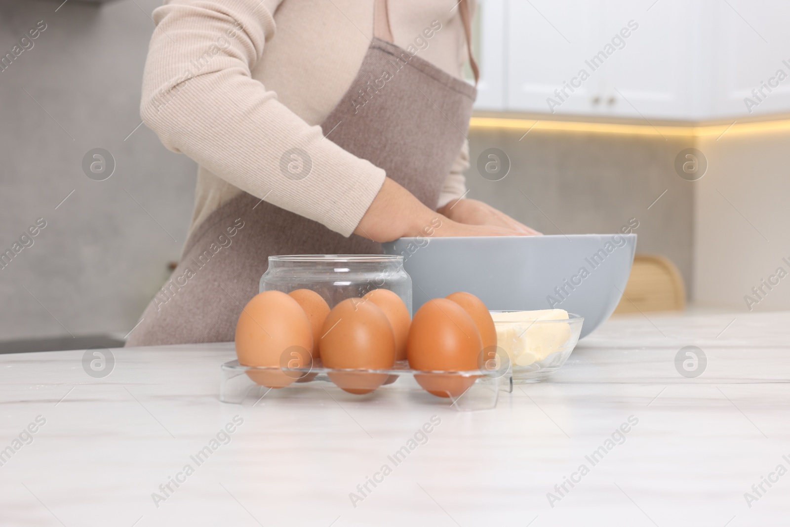 Photo of Woman kneading dough in bowl at white table, closeup