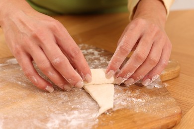 Photo of Woman making croissant at wooden table, closeup