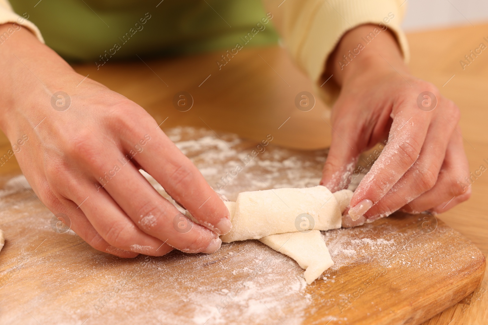 Photo of Woman making croissant at wooden table, closeup