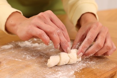 Photo of Woman making croissant at wooden table, closeup