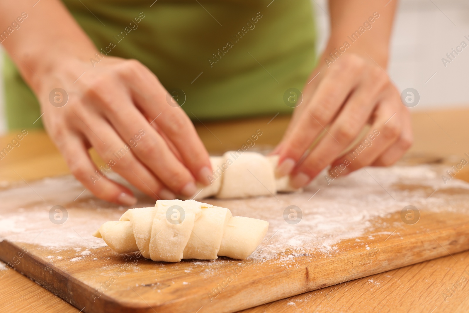 Photo of Woman making croissants at wooden table, closeup