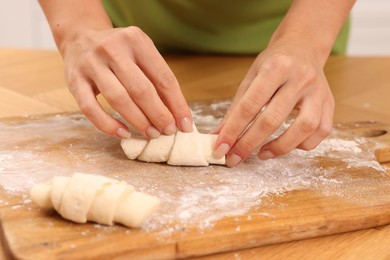 Photo of Woman making croissants at wooden table, closeup