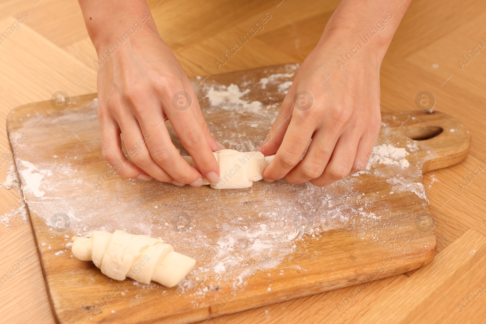 Photo of Woman making croissants at wooden table, closeup