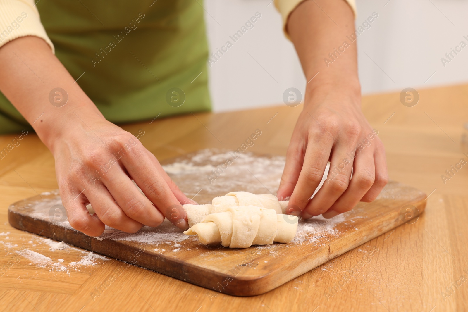 Photo of Woman making croissants at wooden table, closeup