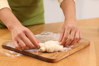 Photo of Woman making croissants at wooden table, closeup