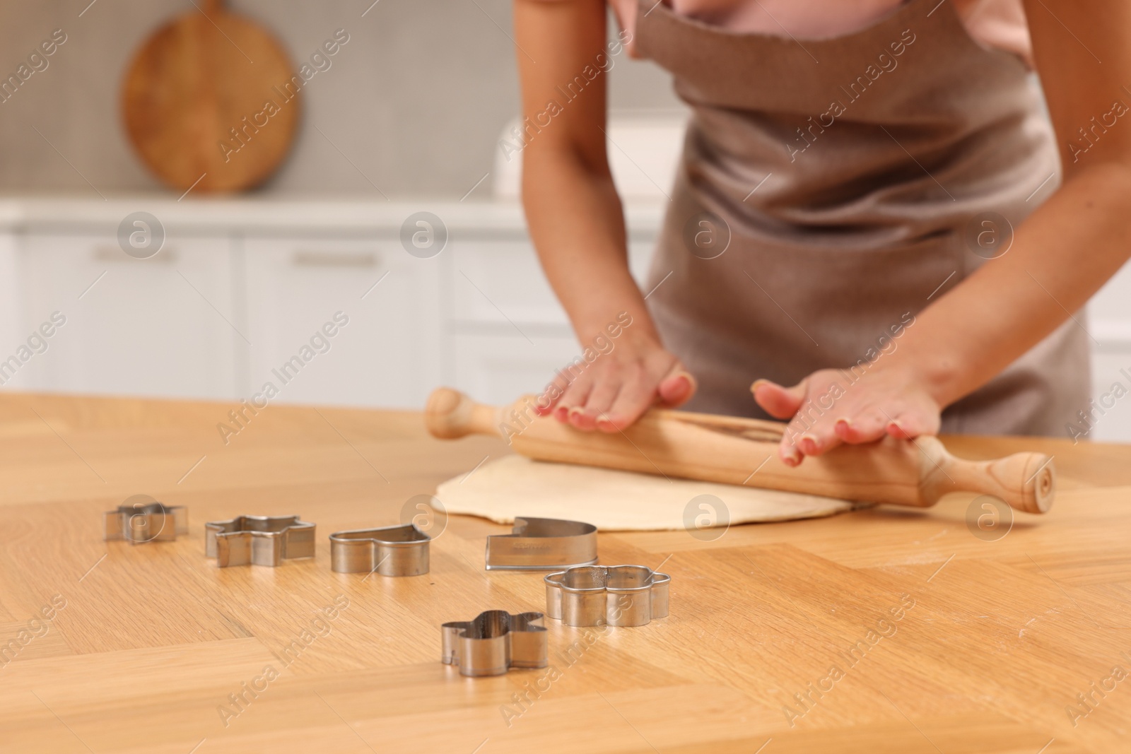 Photo of Woman rolling dough for cookies at wooden table indoors, closeup. Space for text