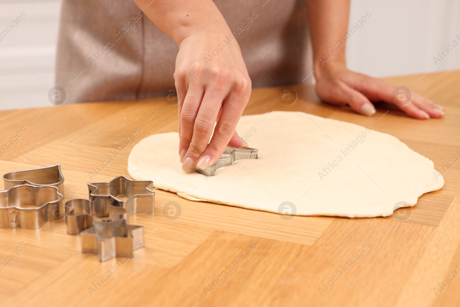 Photo of Woman cutting out cookies at wooden table indoors, closeup